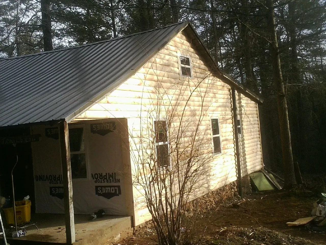 Log siding gable end under a dark metal roof edge in Williams