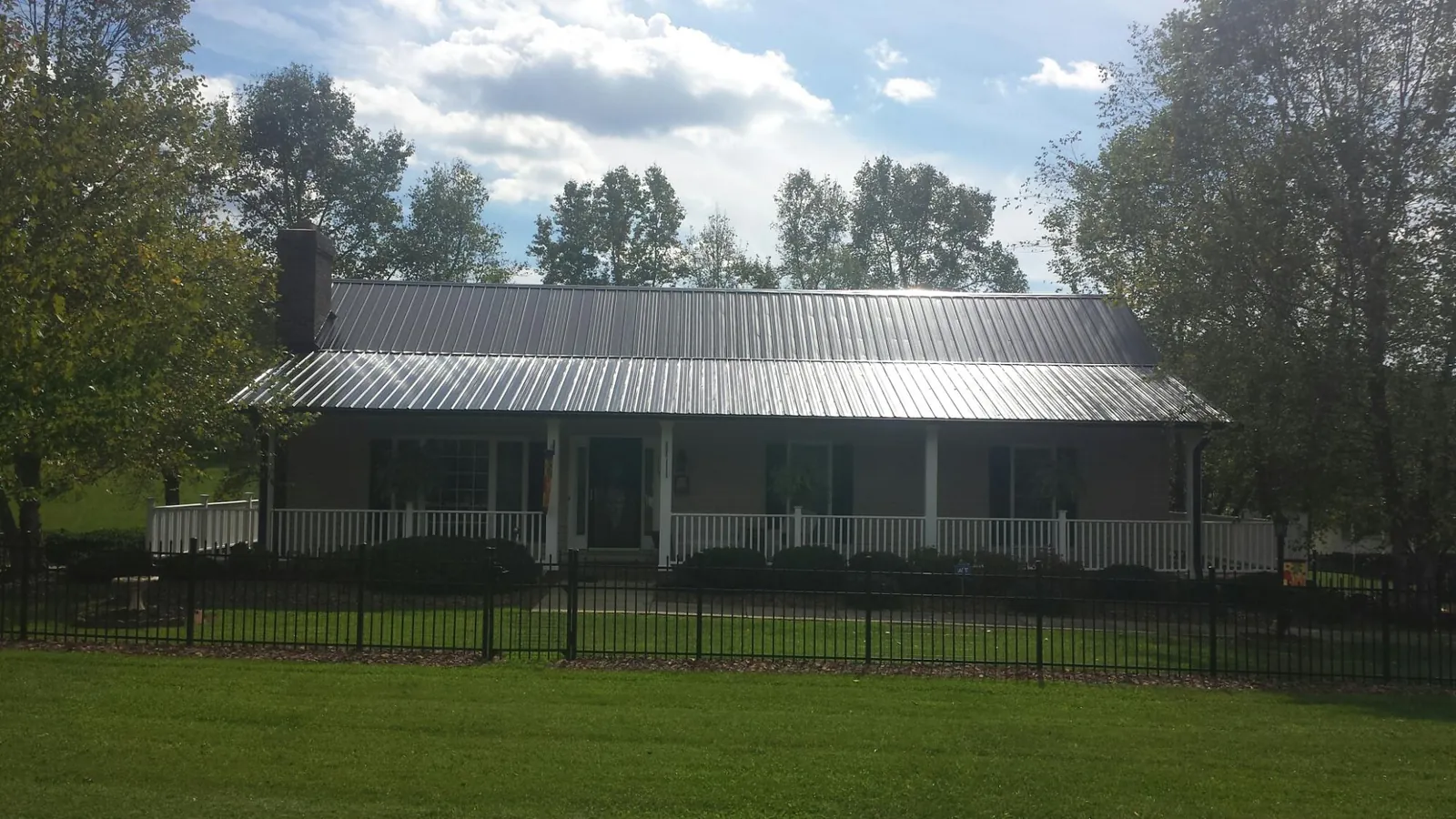 Gray metal roof on a brick ranch with a full width front porch — Gutter Guard Installation work by our crew in Williams